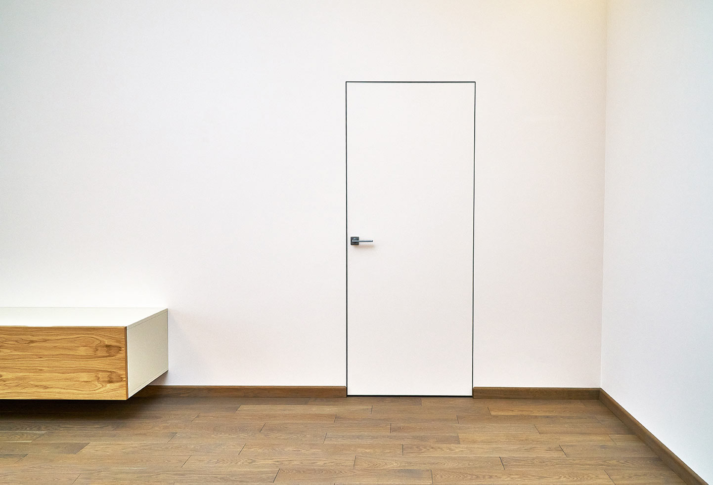 Flächenbündige, rahmenlose Tür in Weiß – harmonische Wandgestaltung für Innenräume Schlichte rahmenlose Tür in Weiß neben Design-Sideboard