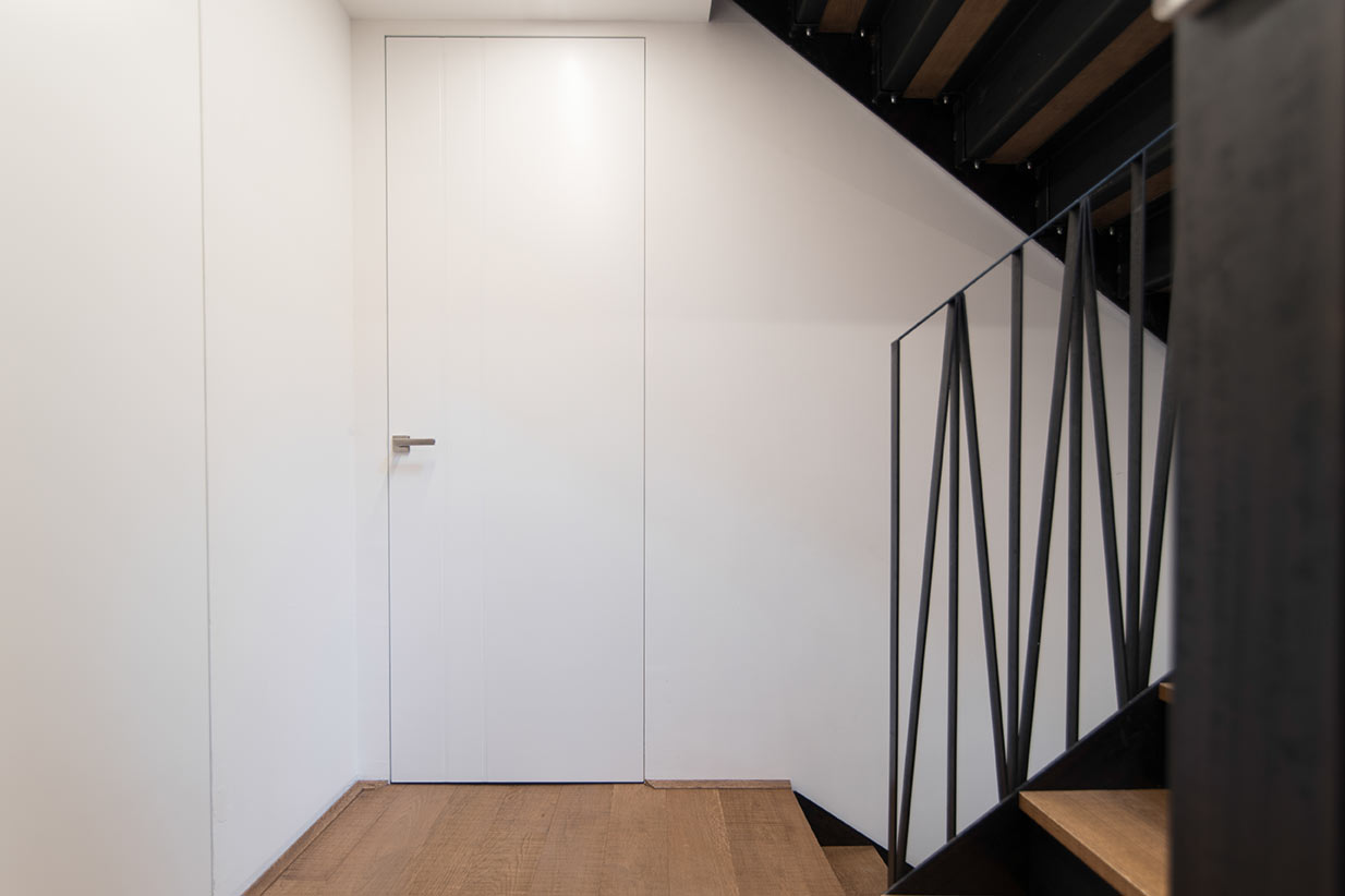 Elegante rahmenlose Tür im Treppenhaus – perfekte Integration in moderne Wohnkonzepte Rahmenlose weiße Tür im modernen Treppenhaus
